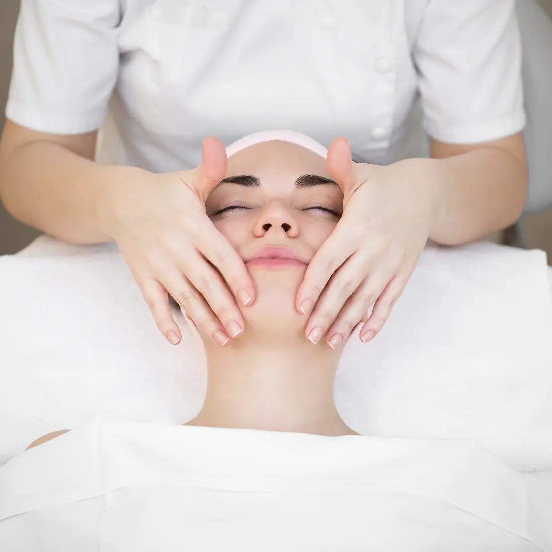 esthetician giving woman facial massage in spa