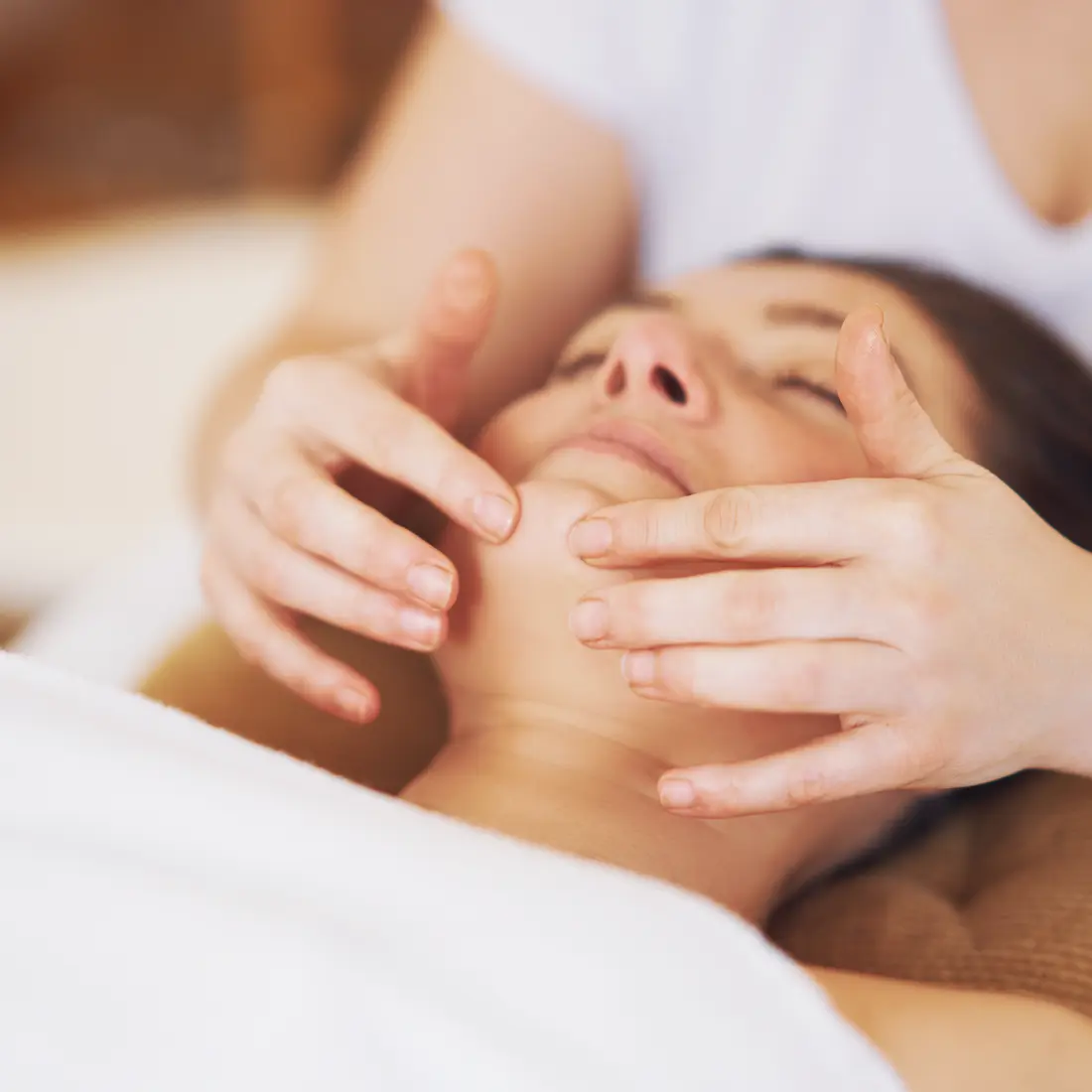 woman receiving facial massage in spa