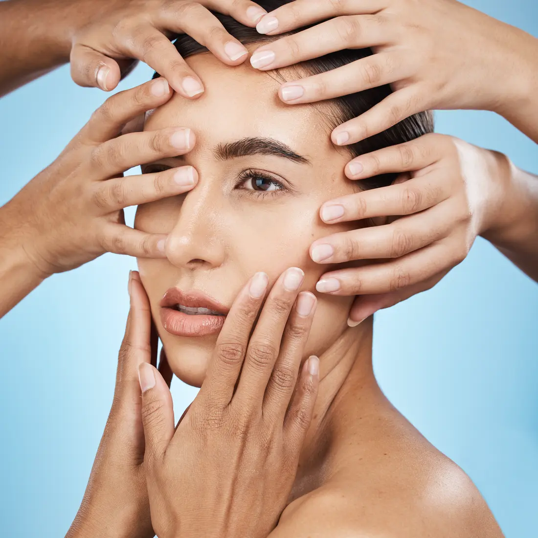 woman's face with multiple hands touching her skin