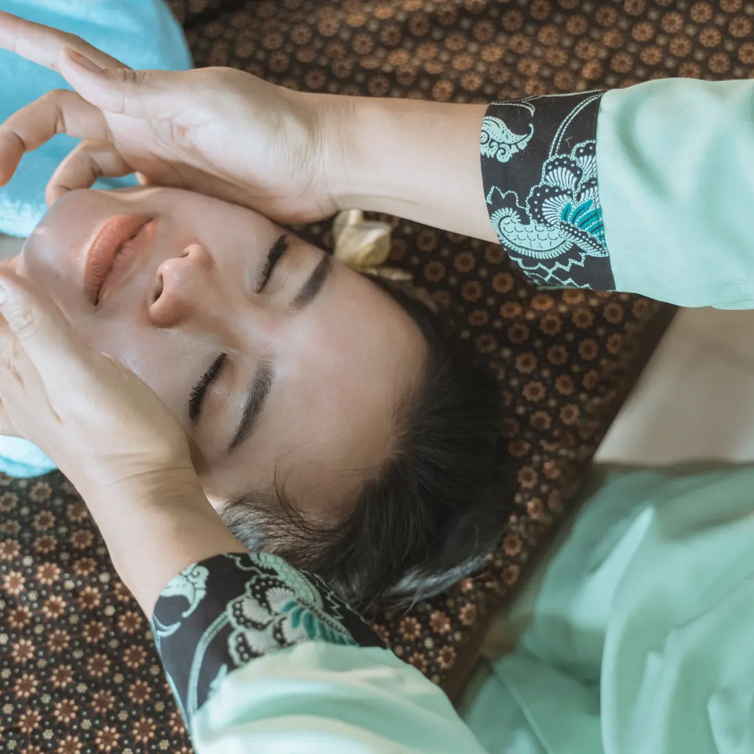 hands massaging a woman's face during a spa treatment