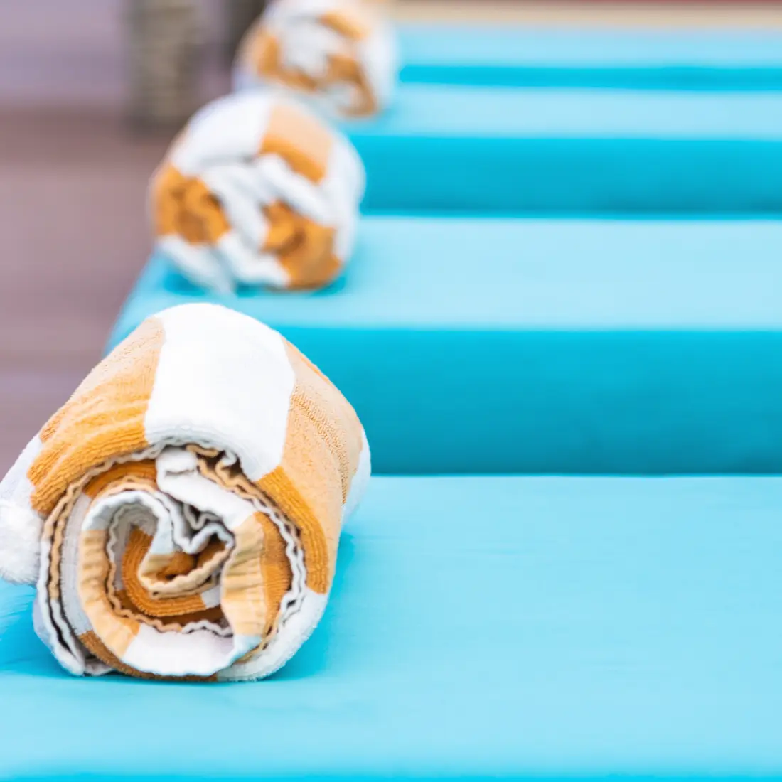 rolled towels on blue lounge chairs