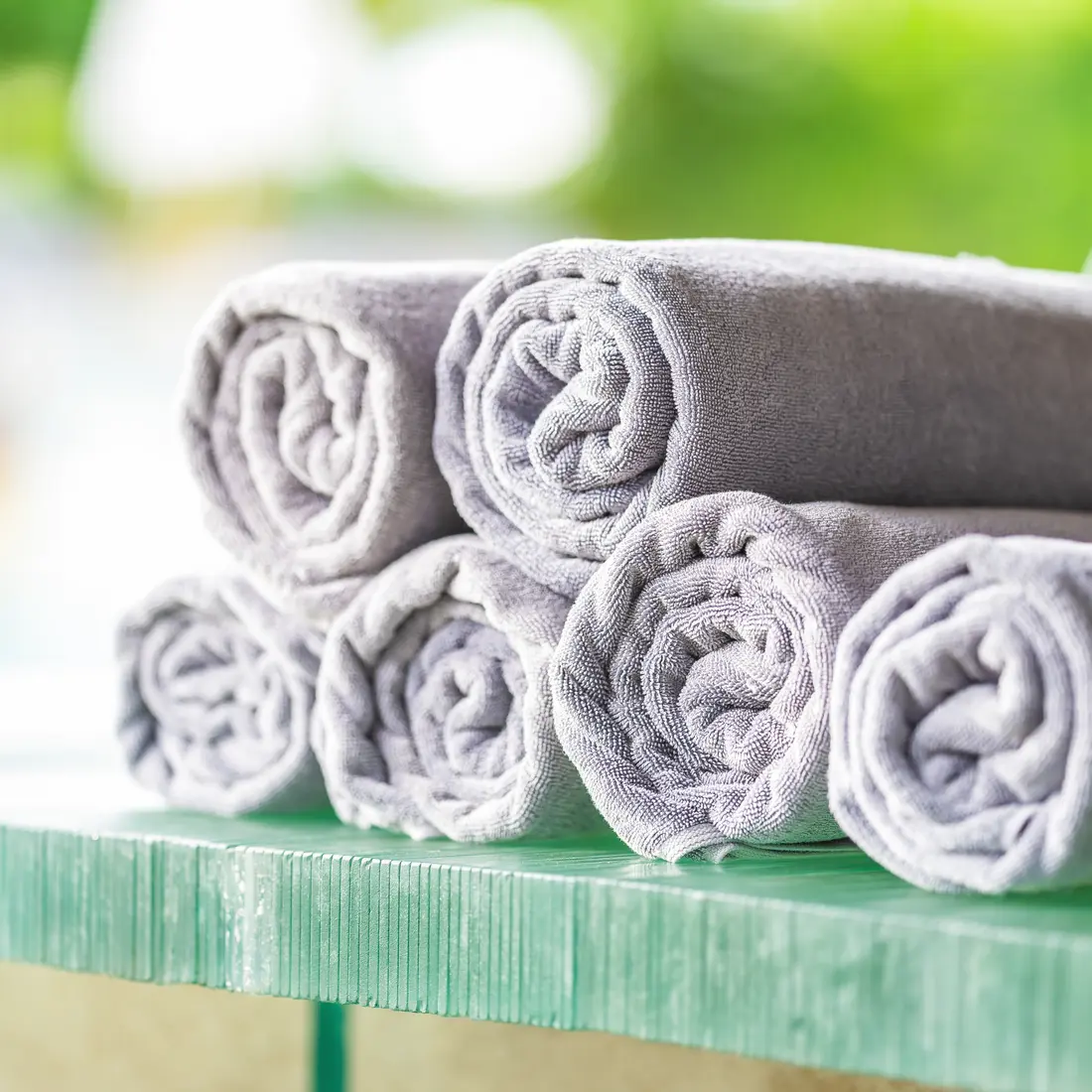 rolled grey towels on a green surface