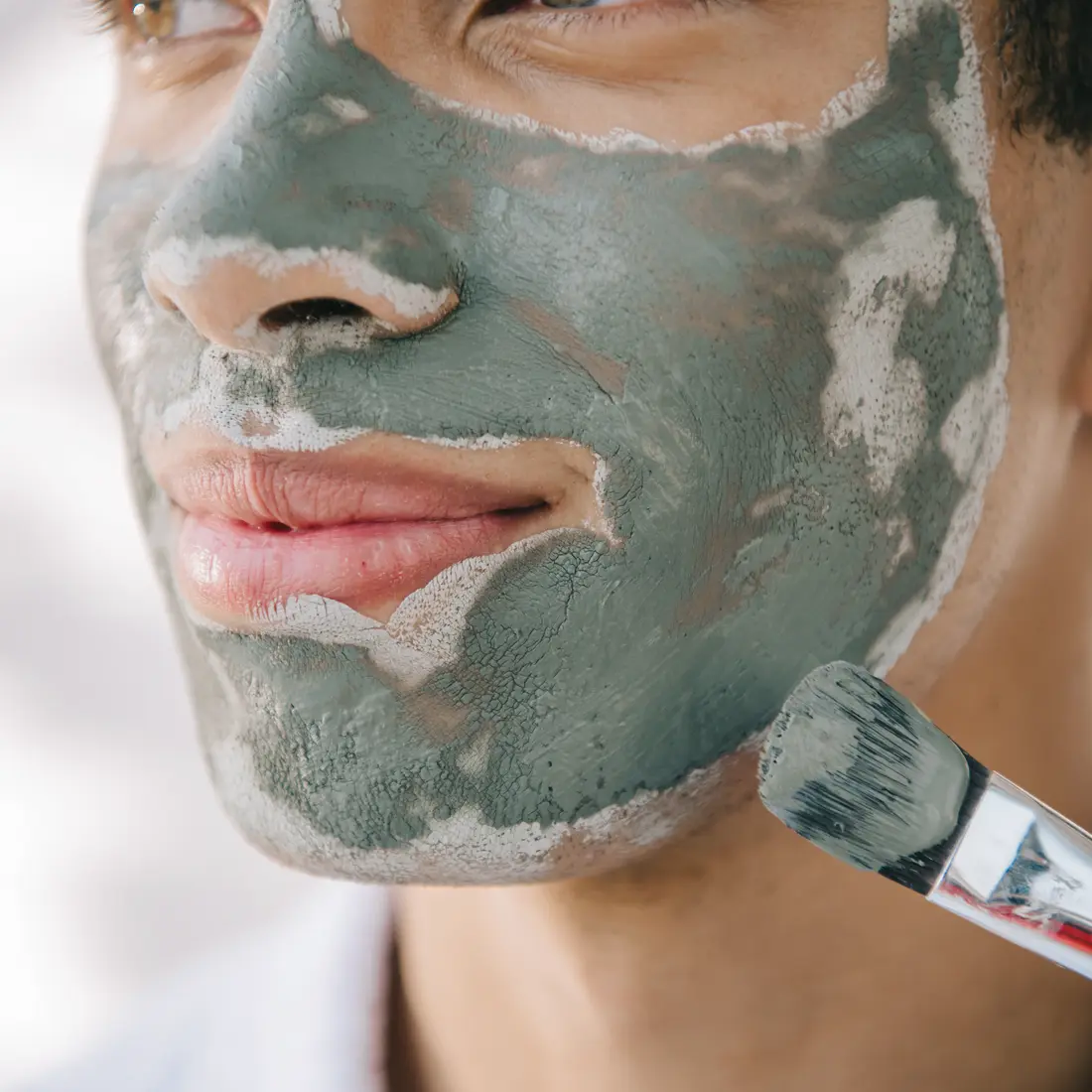 man applying a green clay face mask