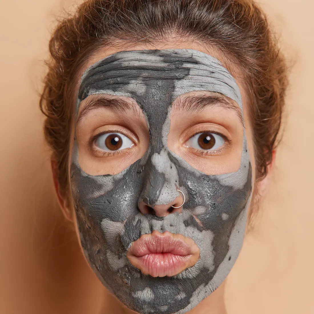 woman with charcoal face mask and puckered lips