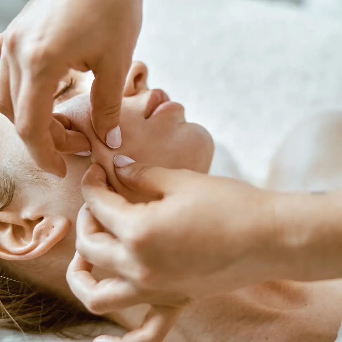 hands massaging a woman's face