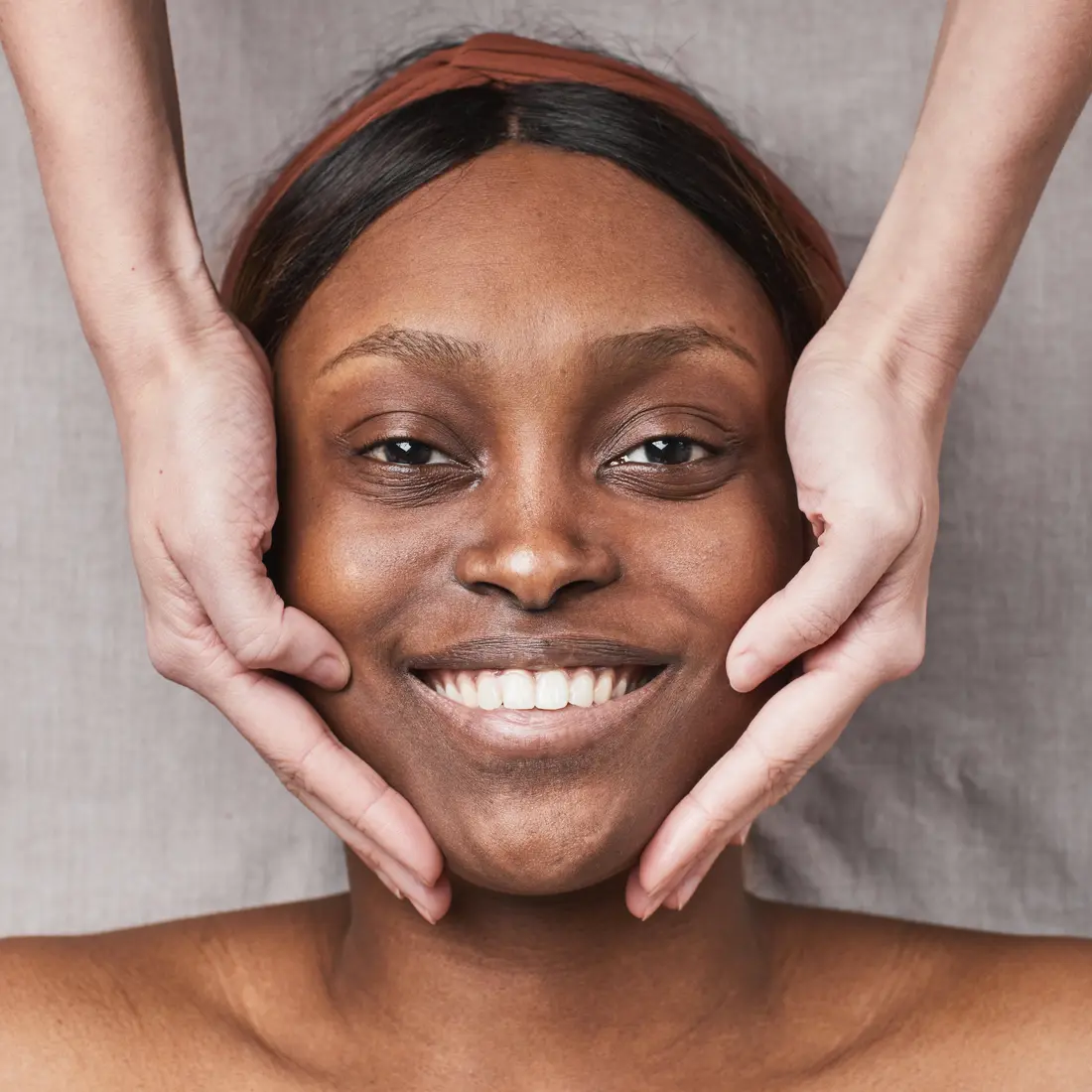 woman receiving a facial massage with hands on cheeks