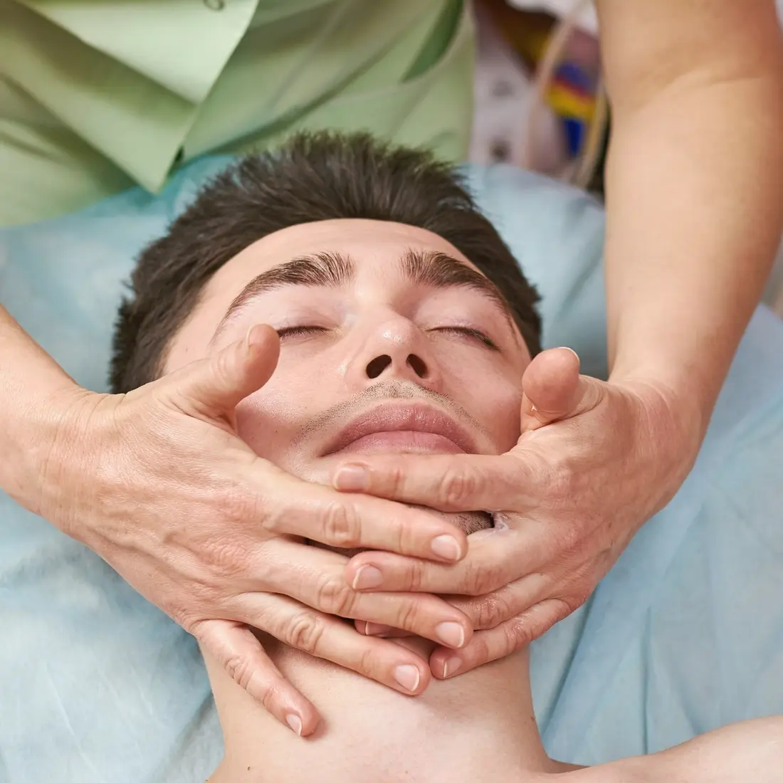 man receiving facial massage in spa