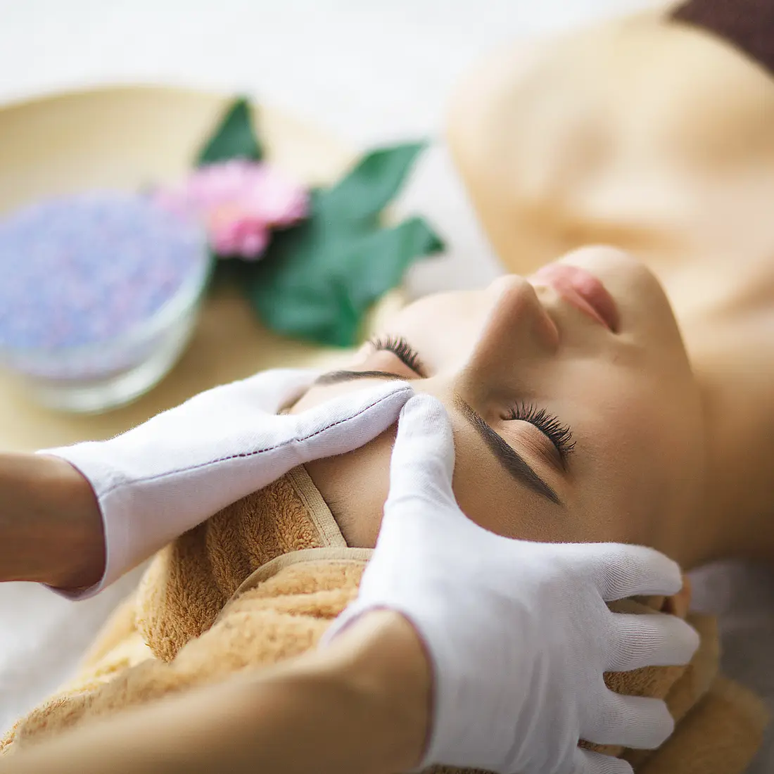woman receiving facial massage with bath salts
