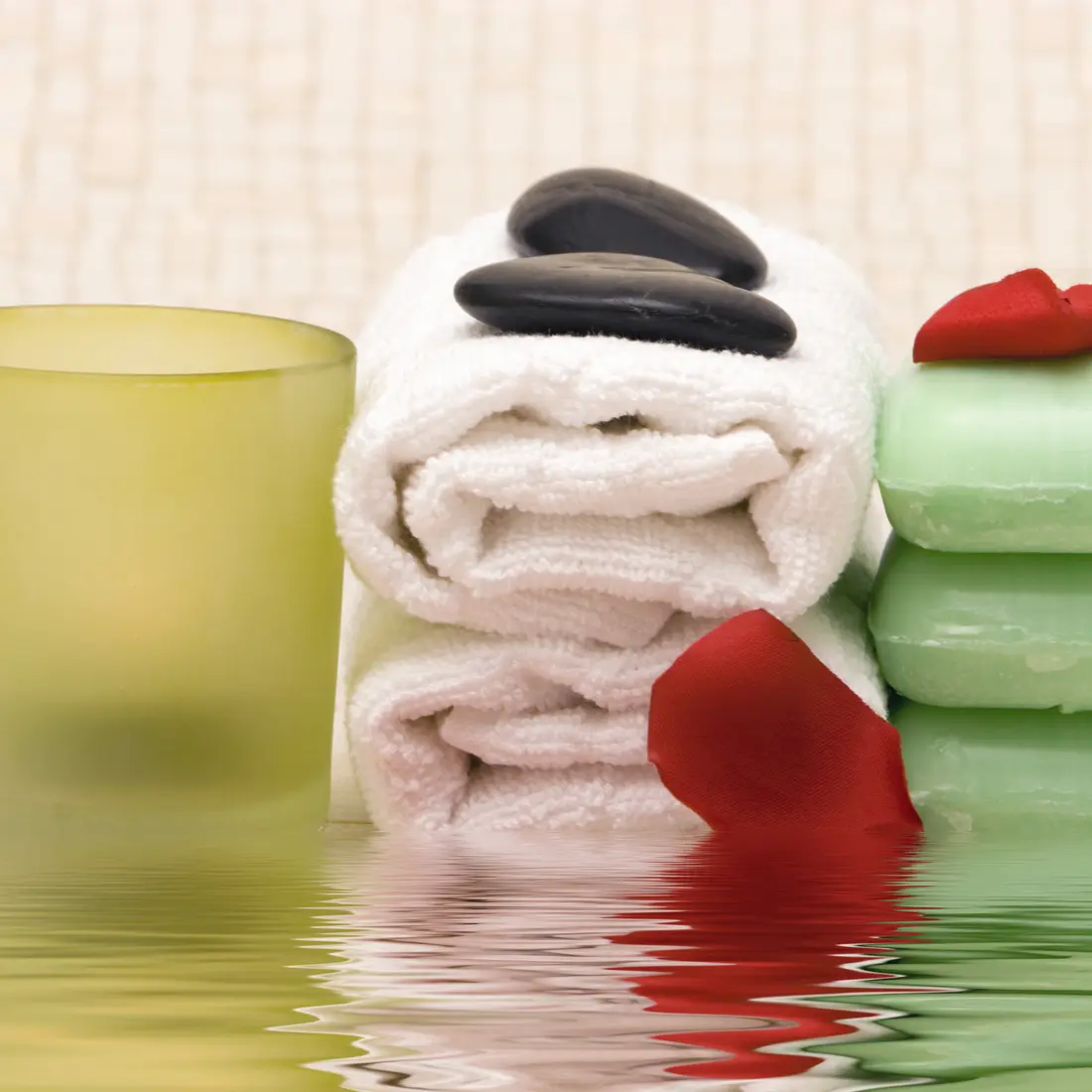 spa items: candle, towels, stones, soap, rose petal