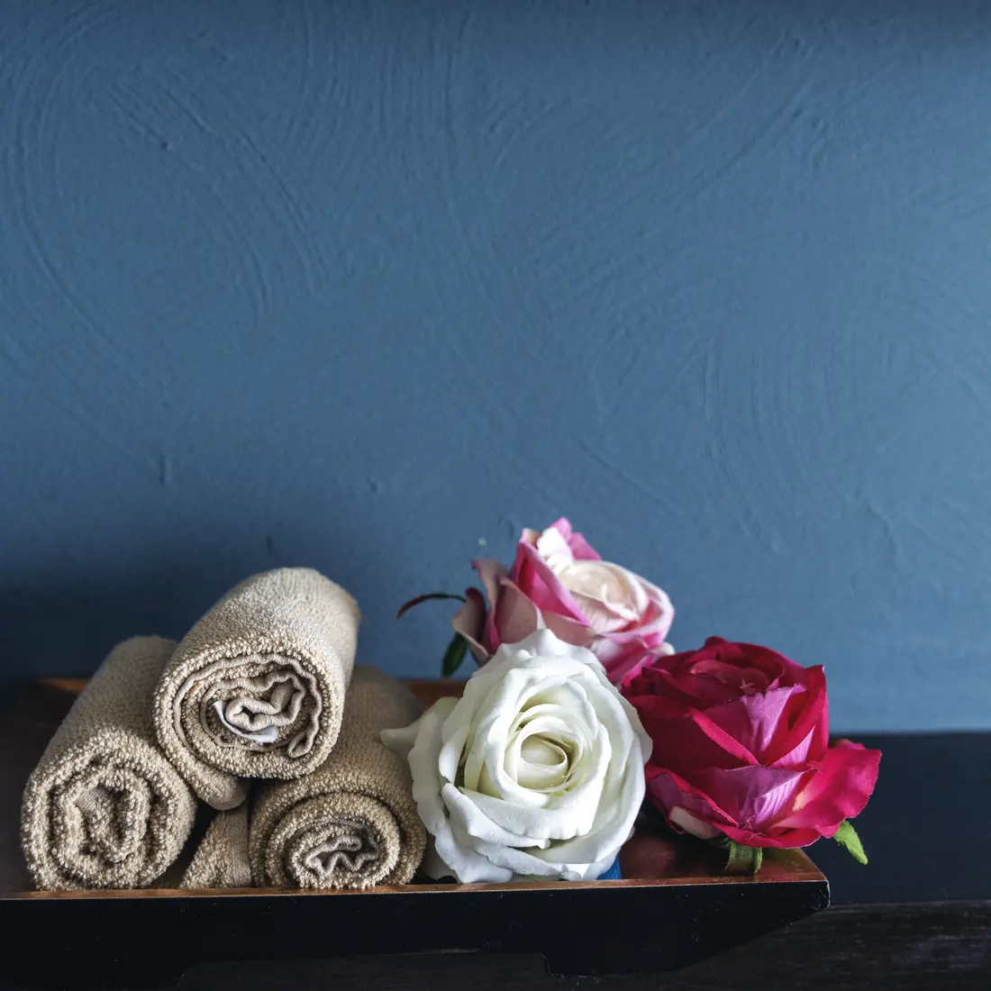 rolled towels and roses on a tray