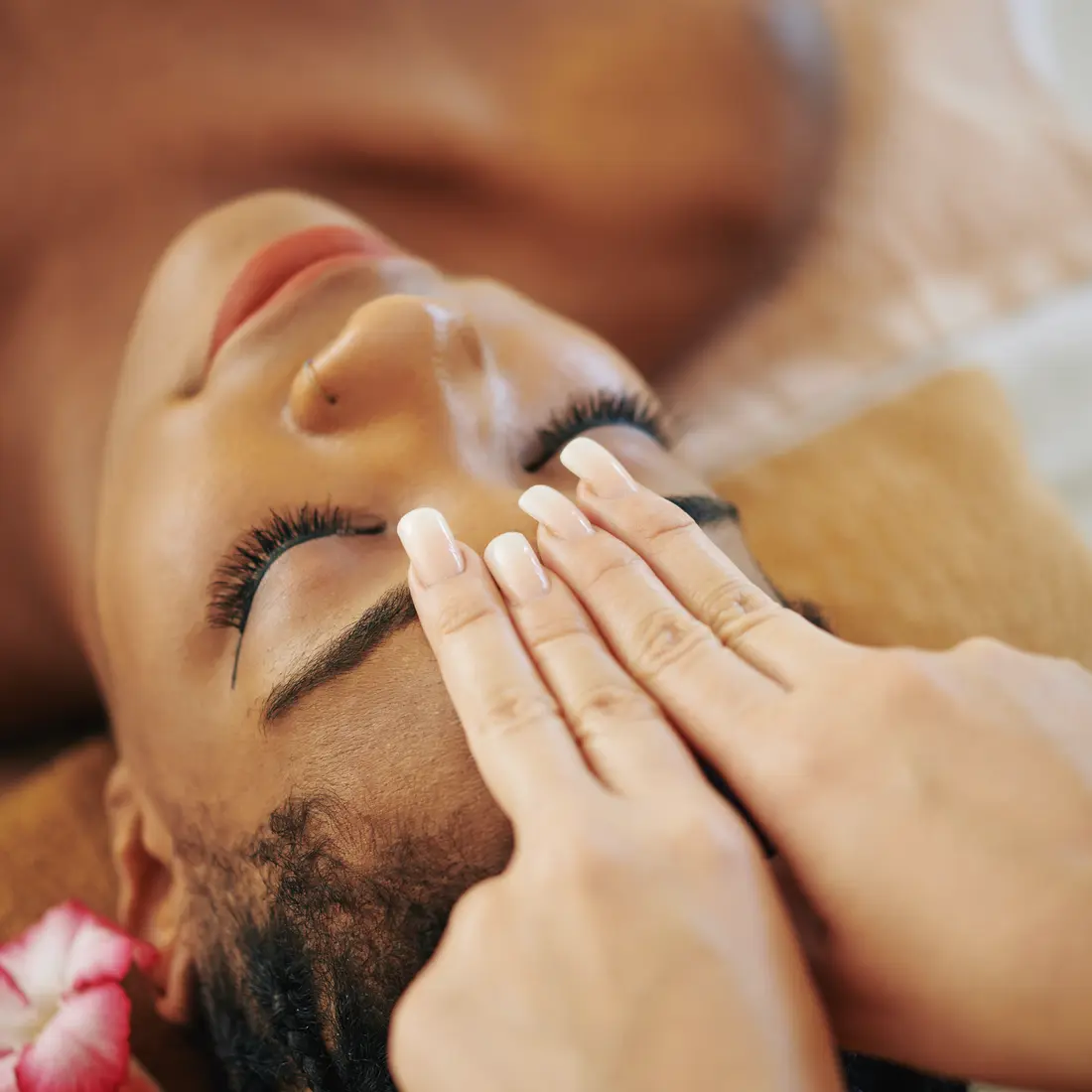woman receiving a relaxing facial massage with a flower