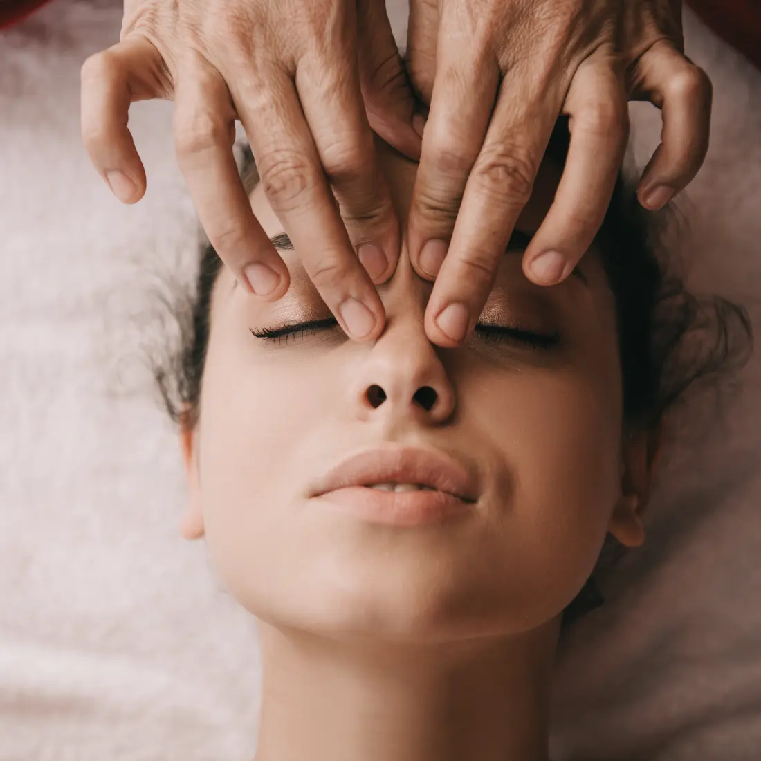 hands massaging woman's face and forehead