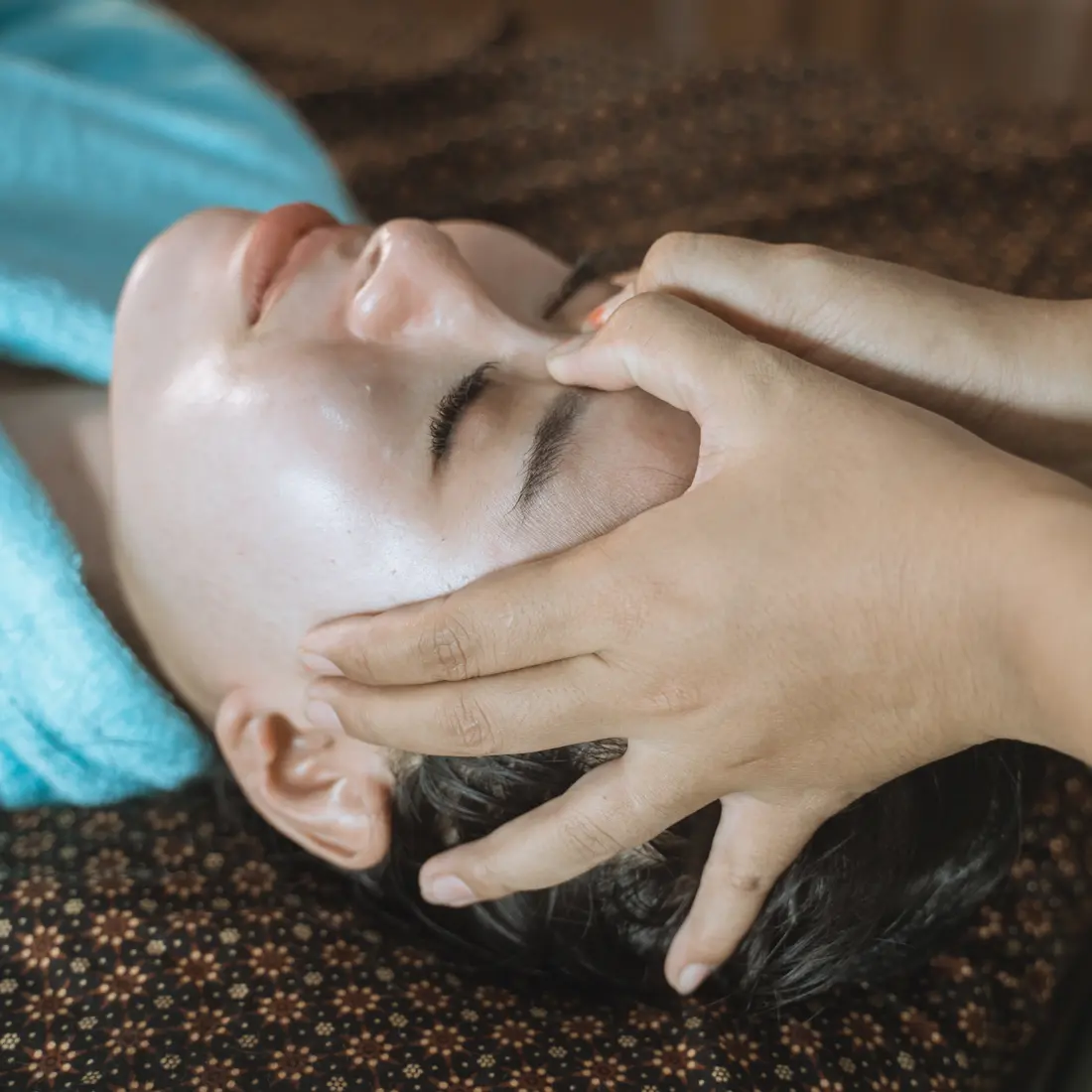 person receiving a facial massage with eyes closed
