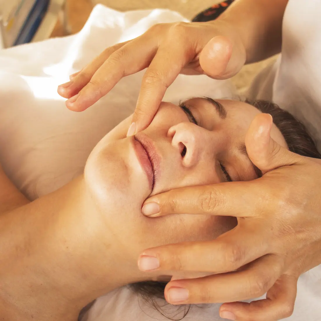 hands massaging a woman's face during a facial