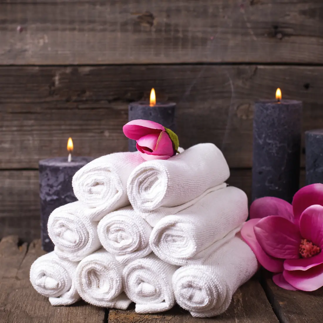 rolled white towels with candles and flowers