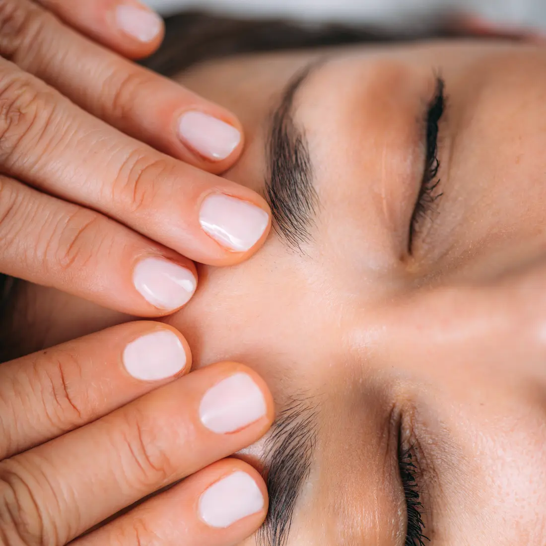 close-up of hands massaging a person's forehead