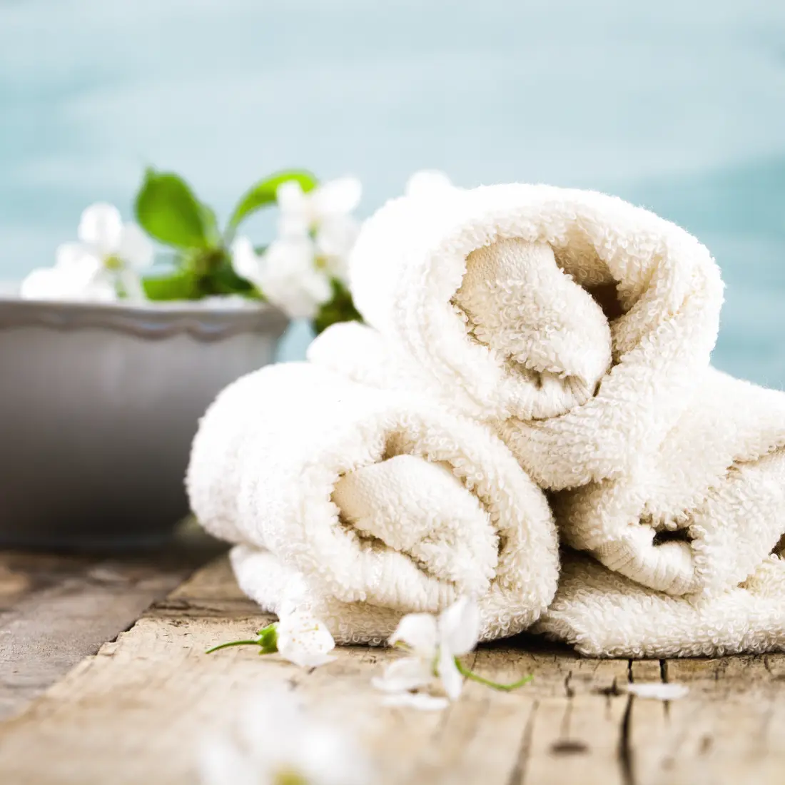 rolled white towels with flowers and bowl