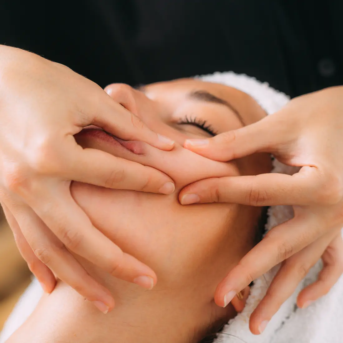 esthetician massaging woman's face with fingers