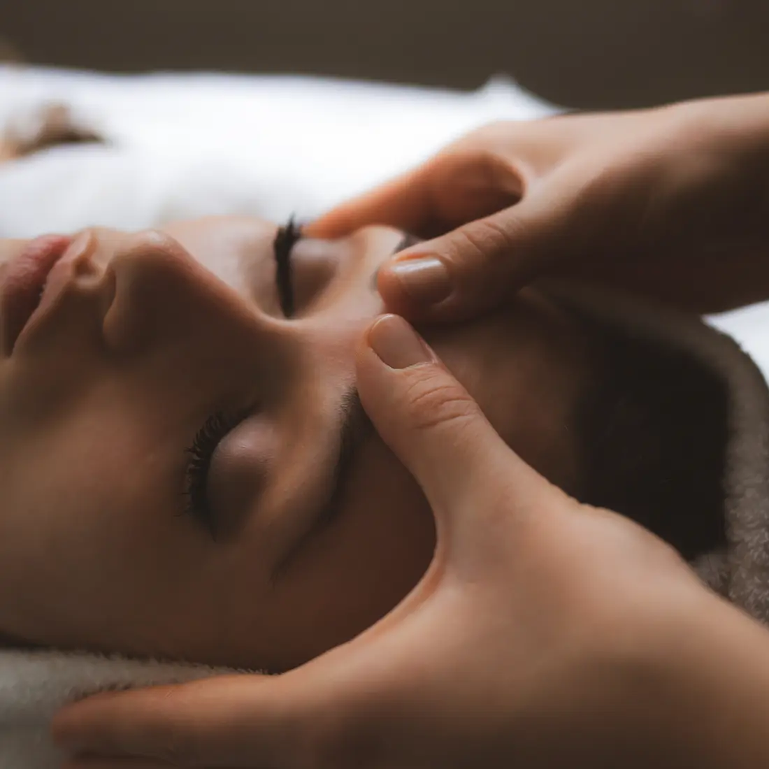 woman receiving facial massage with eyes closed