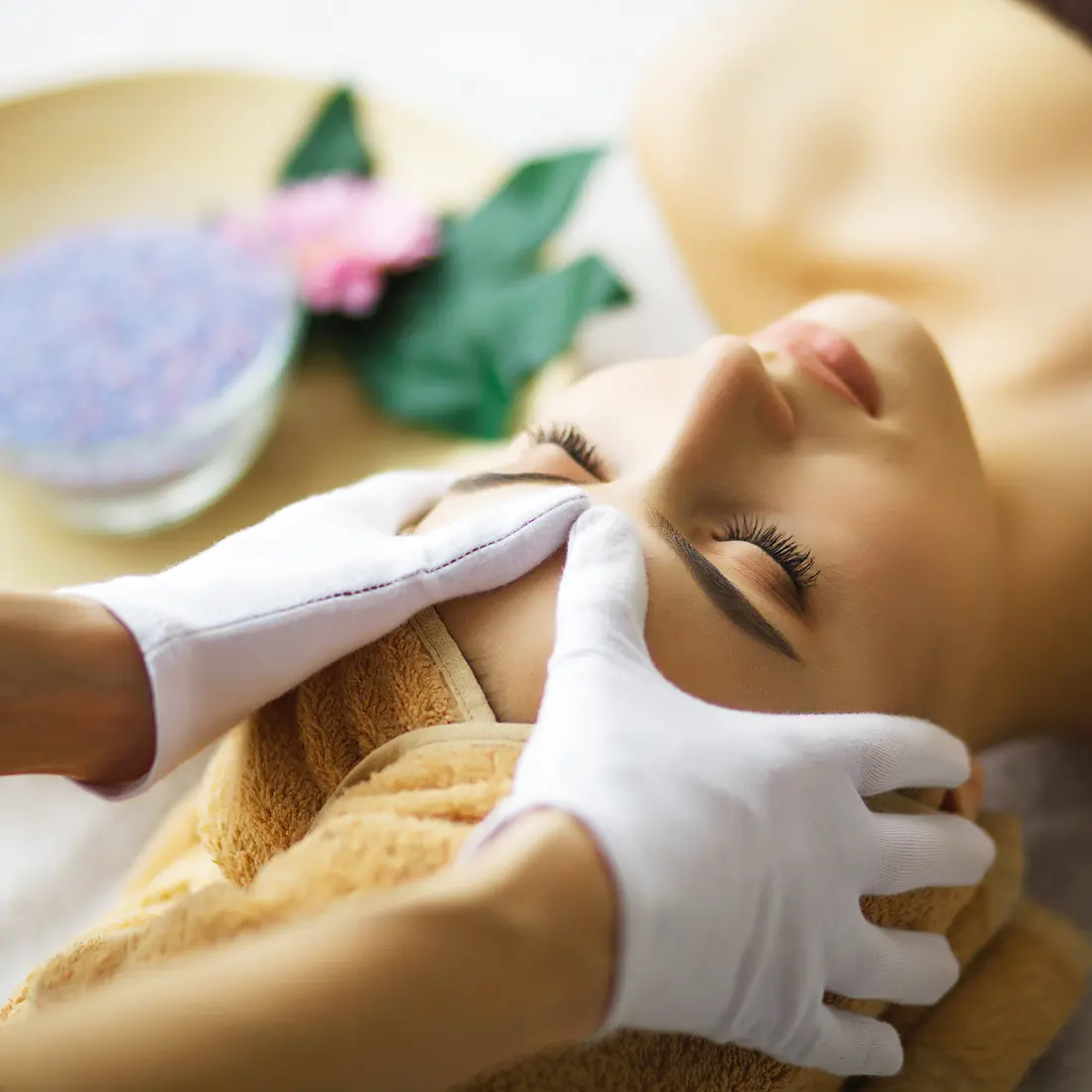 woman receiving a facial massage with white gloves
