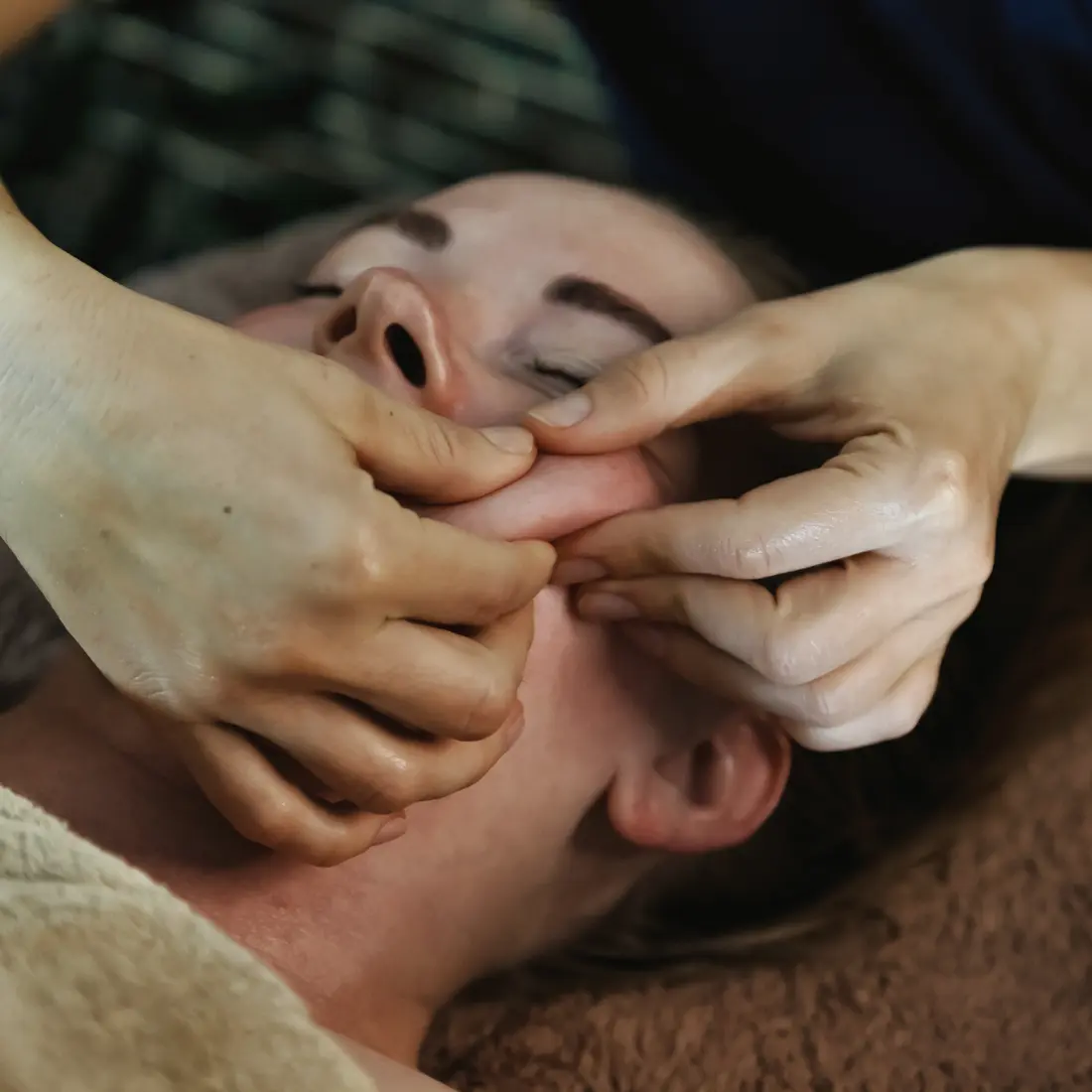 hands massaging a woman's face during a facial