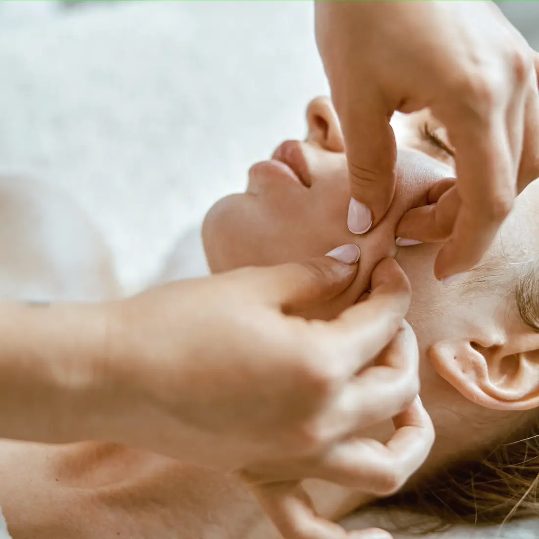 hands massaging a woman's face
