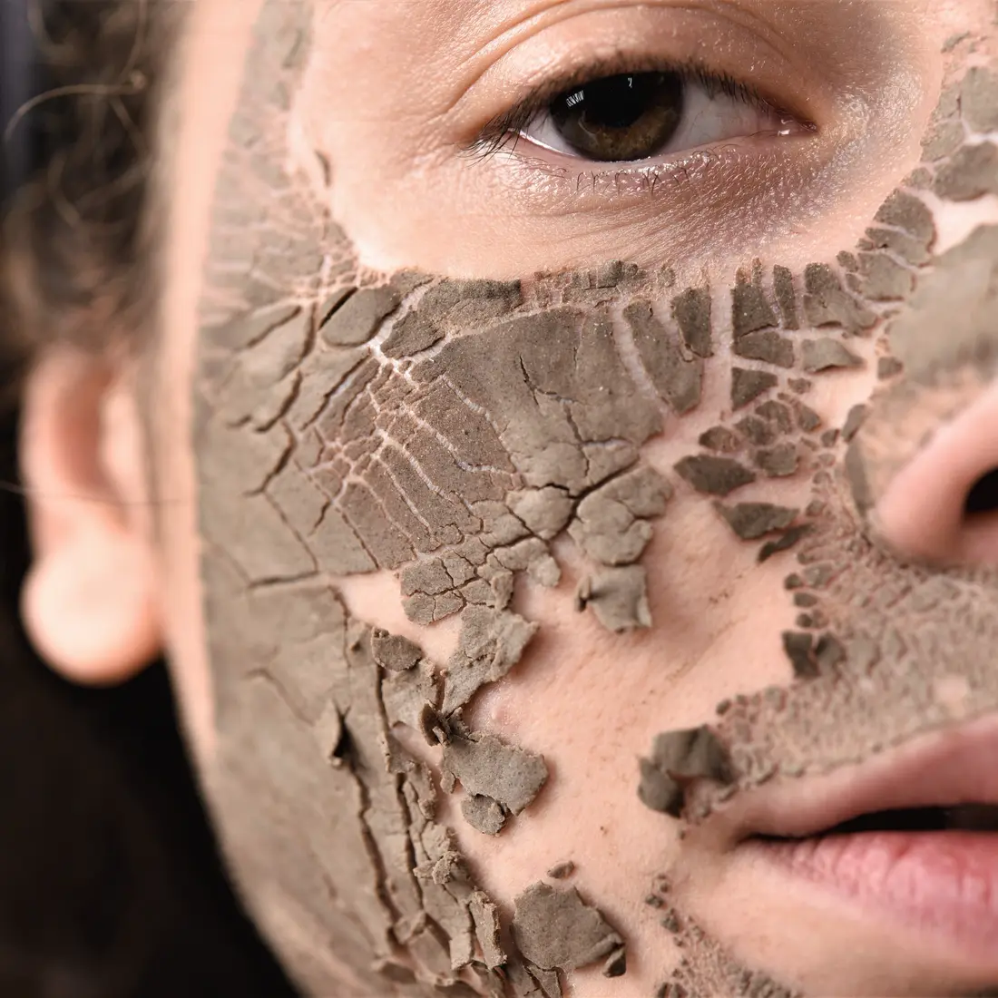 close up of person's face with clay mask