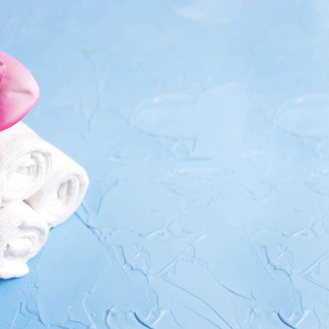 rolled white towels with a pink magnolia flower