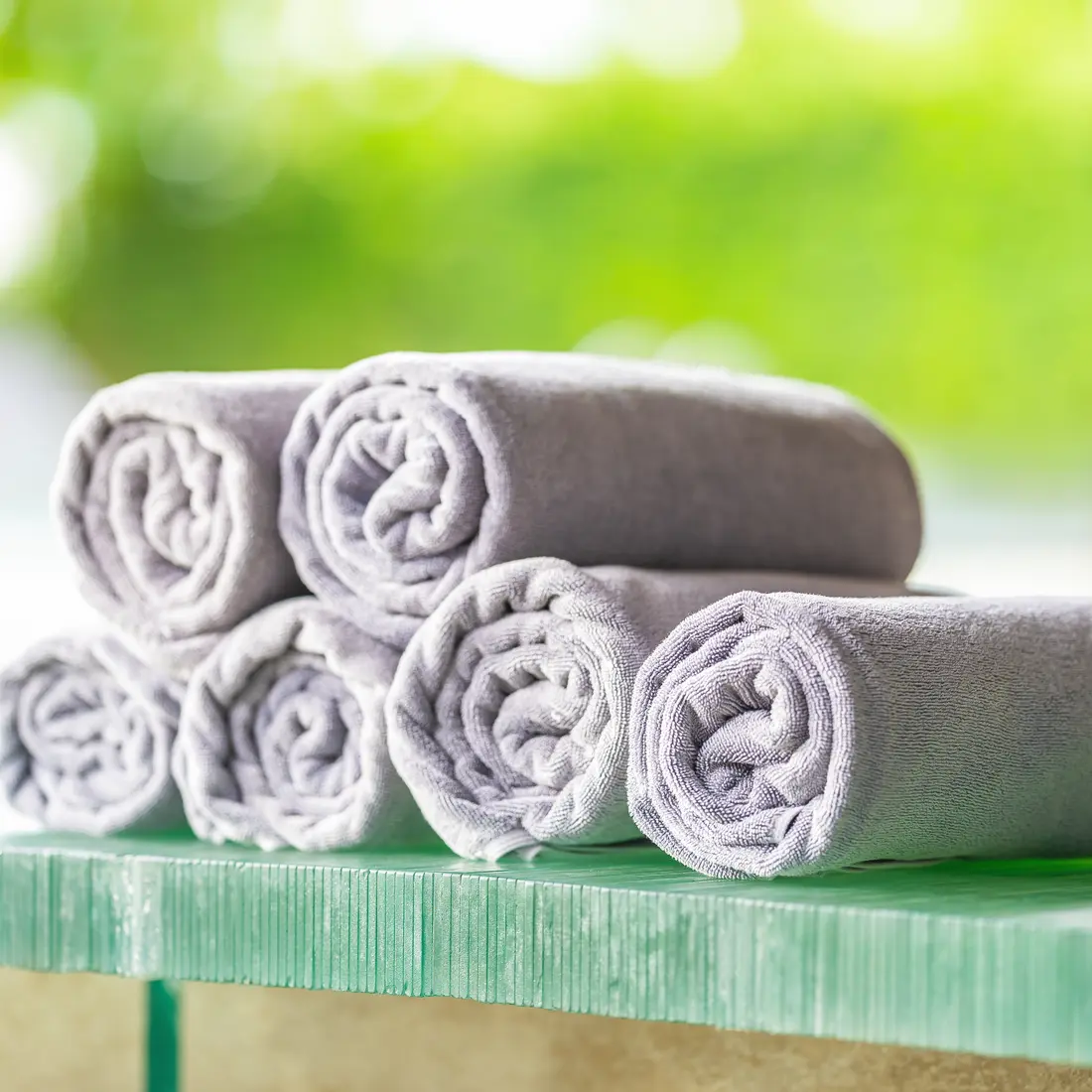 rolled gray towels on a glass surface