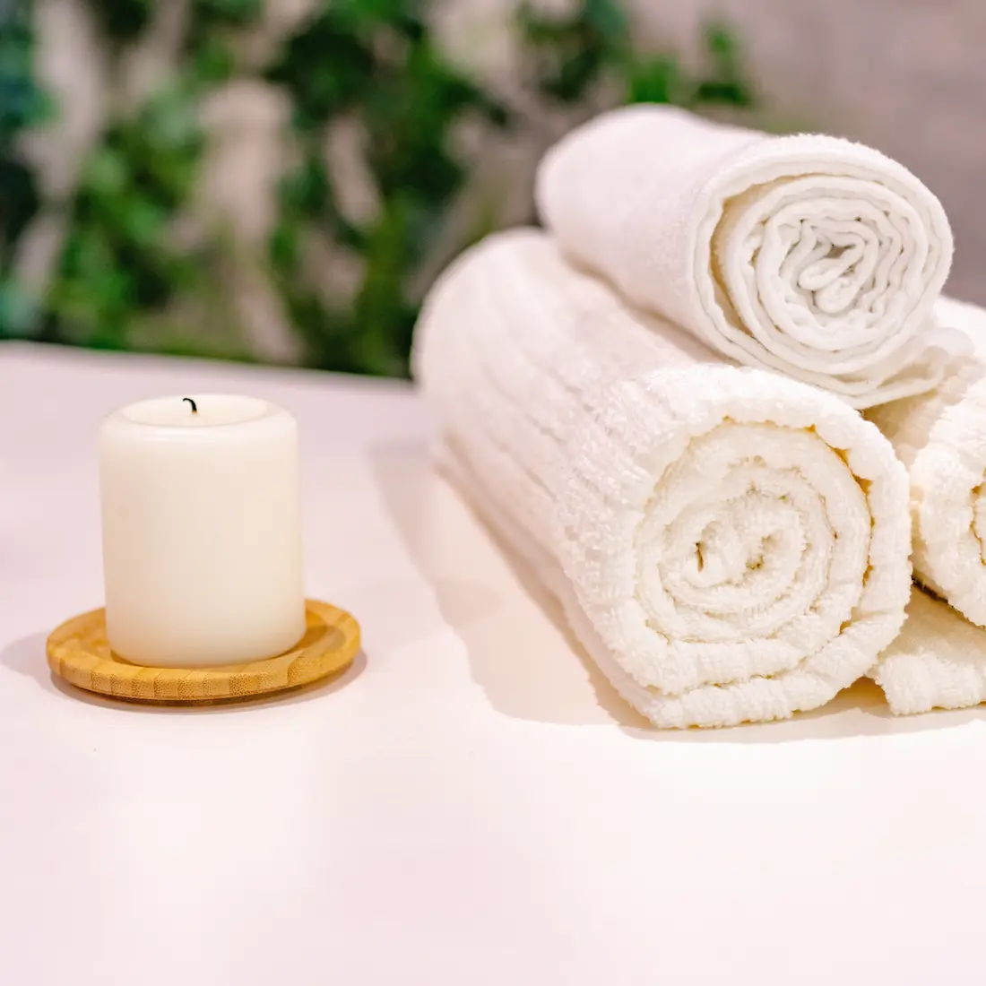 rolled white towels and a white candle
