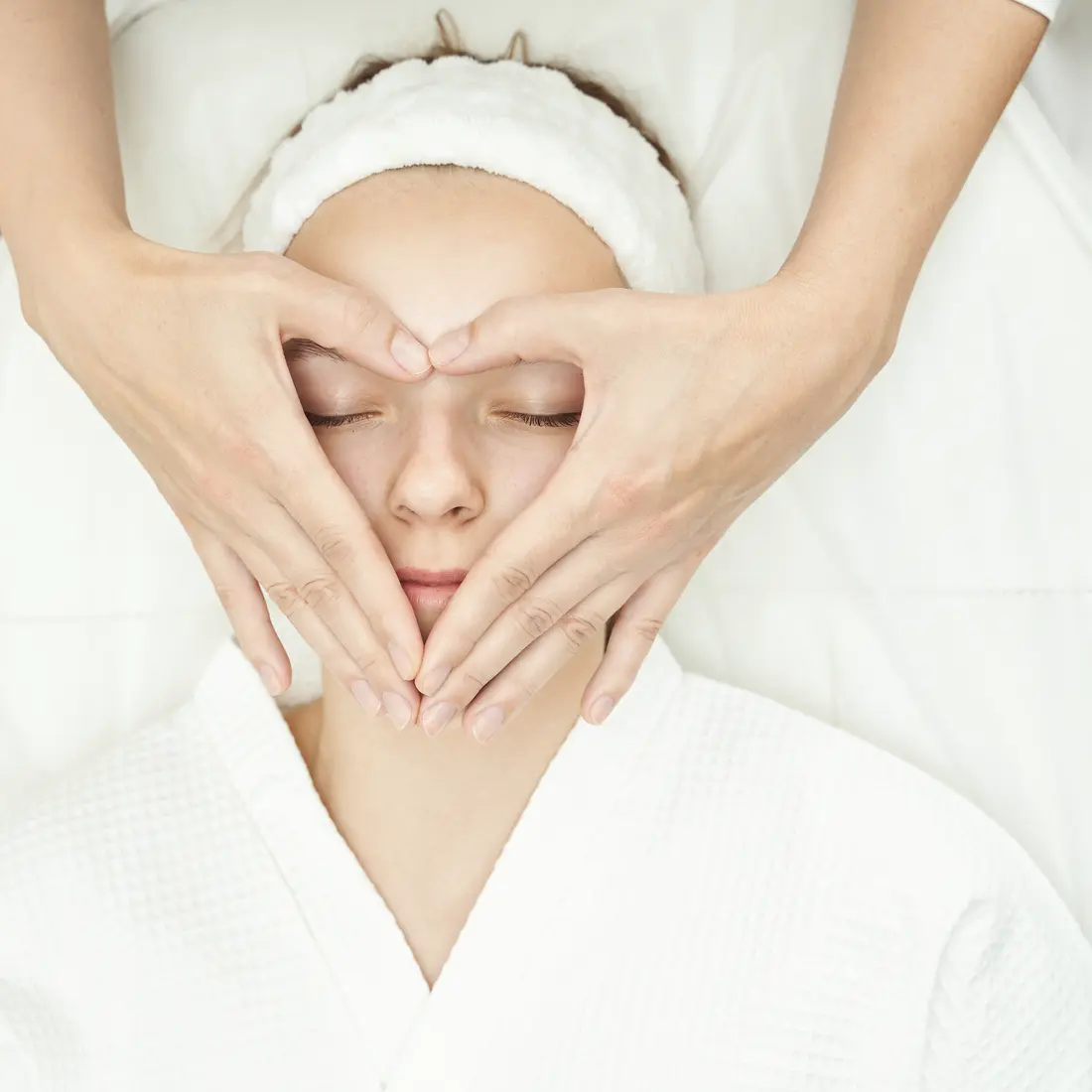 hands giving facial massage in heart shape