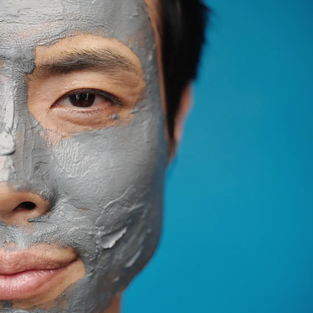 man with clay mask on half his face