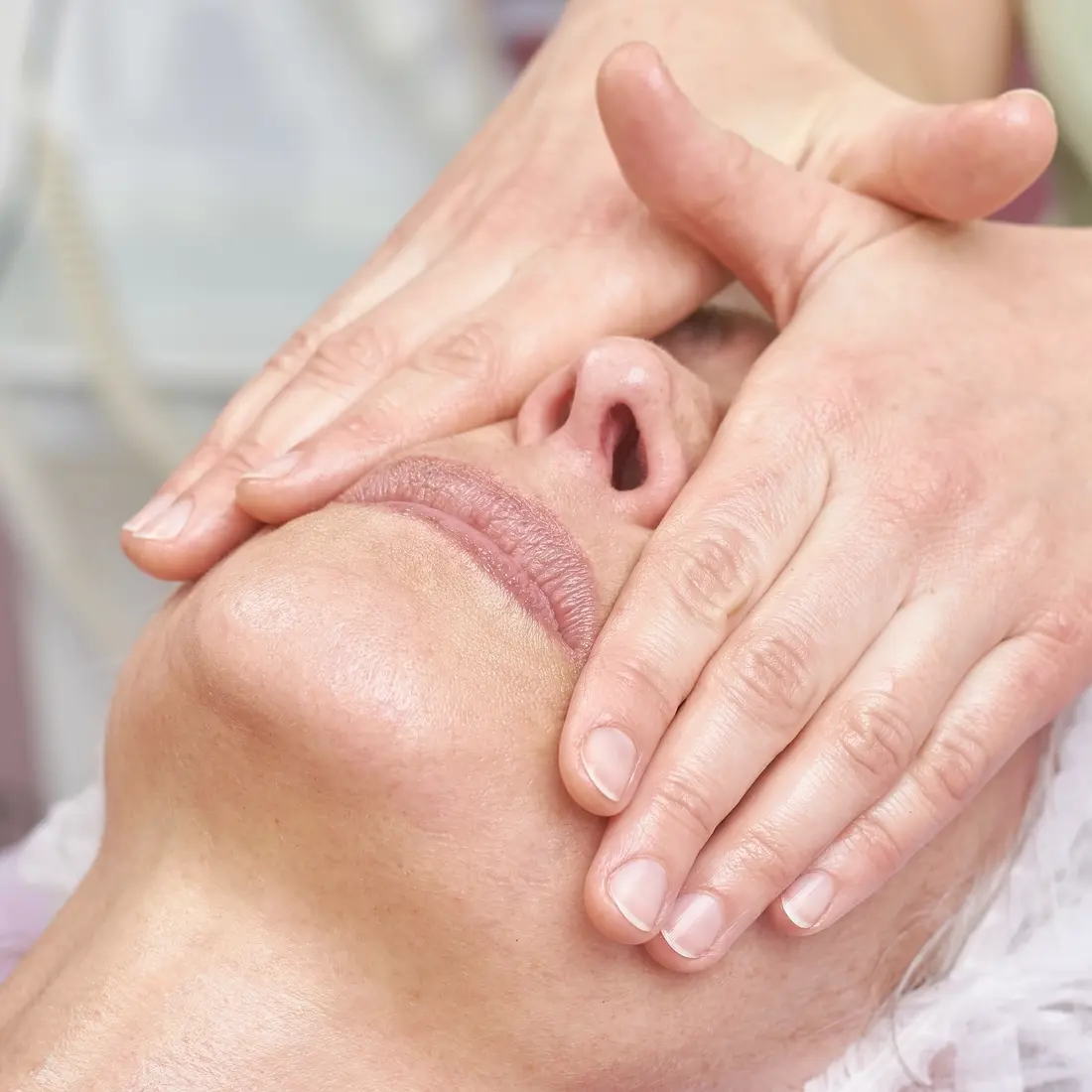 hands massaging a woman's face during a facial
