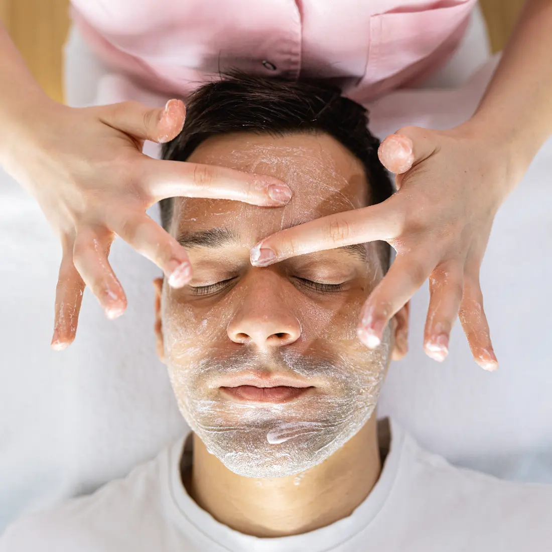 man receiving facial massage with cream