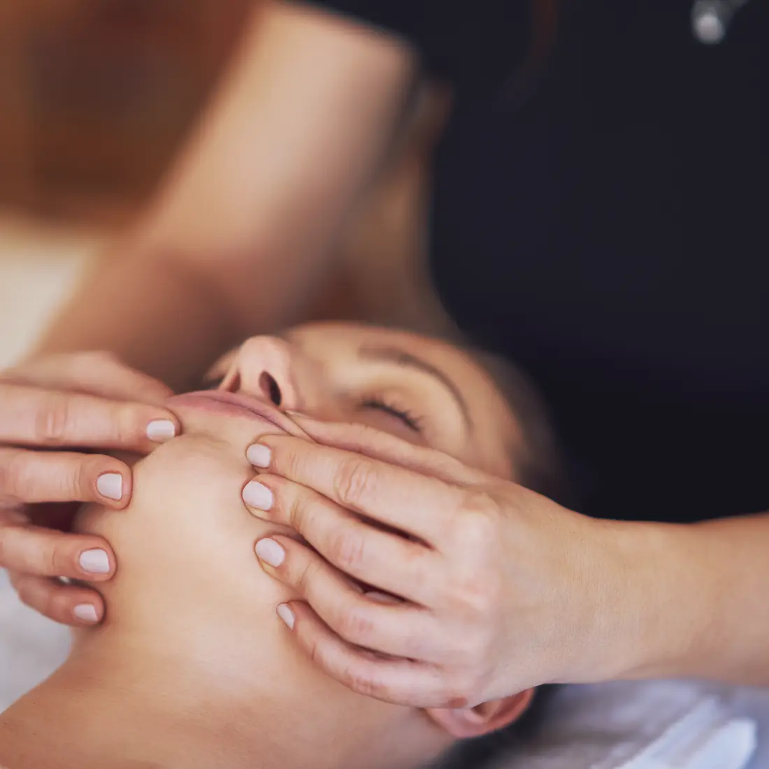 hands massaging a woman's face