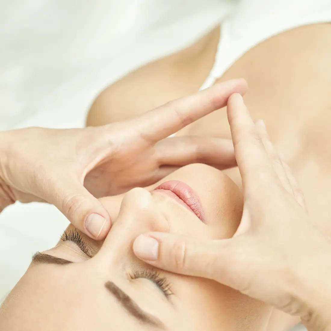 close up of hands massaging a woman's face