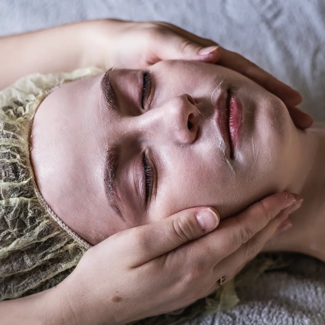 woman receiving facial massage with cap on