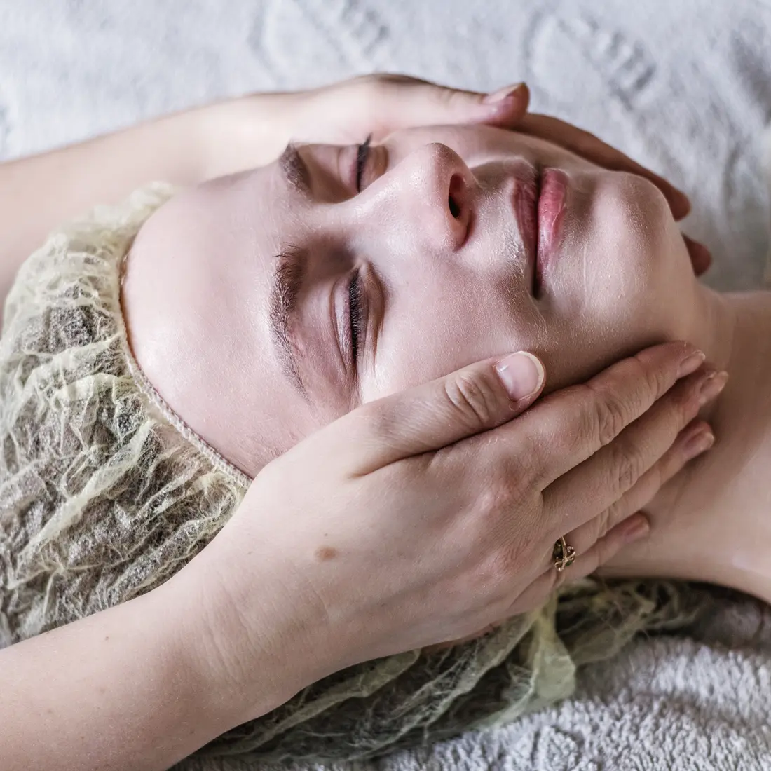 person receiving a facial massage with a hair net